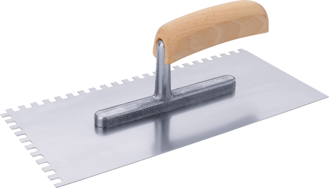 Truelle rectangulaire à dents avec lame métallique polie et poignée en bois courbée ; un long côté présente des encoches carrées régulières et la fixation métallique est estampillée « Made in Germany ». 