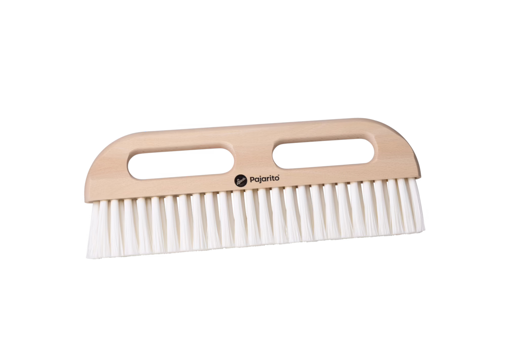 Pajarito_Dummy_Wallpaper squeegee nylon P-Line_179112_2024-02 Une brosse en bois avec une large poignée et des poils blancs. Elle présente deux poignées découpées pour une prise en main facile, conçue pour le nettoyage ou le toilettage.