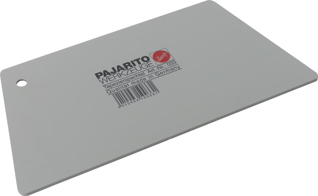 Spatule à tapisser rectangulaire en plastique gris, posée en diagonale sur fond blanc, coins arrondis et trou de suspension sur un côté court. Impression noire au centre 'PAJARITO WERKZEUGE' avec la mention 'Tapezierspachtel Art.-Nr.: 033 Qualität made in Germany' et un code-barres en dessous. Lame plate et lisse utilisée pour lisser les papiers peints et répartir la colle.