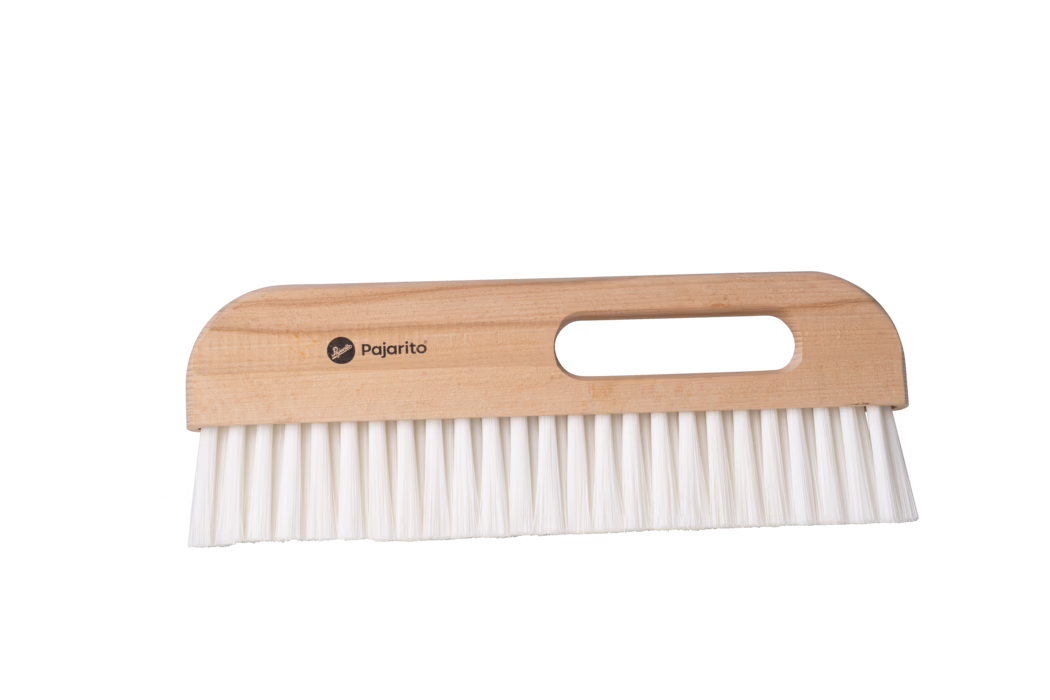 Pajarito_Dummy_Wallpaper wiper Nylon E-Line_179058_2024-02 Une petite brosse en bois avec des poils blancs, dotée d'une poignée pour une prise facile. La brosse a un sommet arrondi et des poils droits alignés uniformément. Le nom de la marque 'Pajarito' est imprimé sur la poignée en bois.