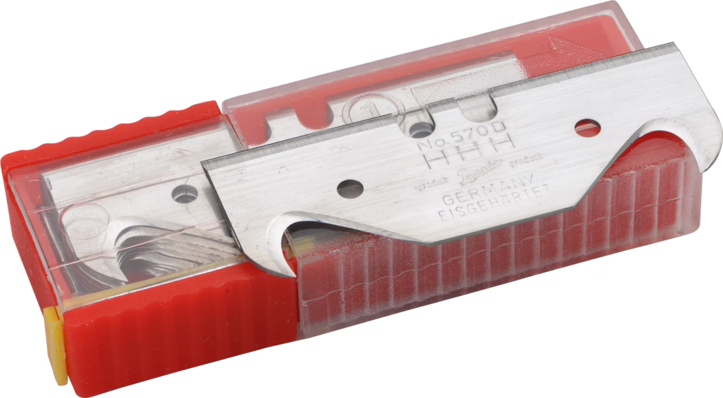 Pajarito_Dummy_Double ground blades_034584_2021-02 Une vue en gros plan d'une lame de rasoir dans un boîtier rouge de protection, la lame étant visible montrant son tranchant. La lame présente une gravure indiquant qu'elle est fabriquée en Allemagne et son numéro de modèle. Le boîtier est transparent sur le dessus, permettant de voir la lame à l'intérieur, et a une texture nervurée sur les côtés pour une meilleure prise.