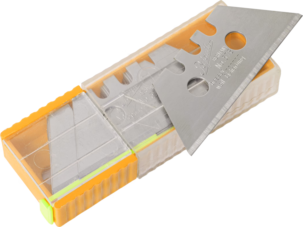 Une image en gros plan d'une lame utilitaire en métal logée dans un boîtier en plastique transparent. La lame est argentée et tranchante avec des encoches sur le bord, reflétant la lumière. Le boîtier a un côté orange et comprend des couleurs d'accent jaune et verte, et est conçu pour maintenir la lame en toute sécurité tout en permettant la visibilité. L'arrière-plan est neutre, se concentrant sur la lame et son boîtier.