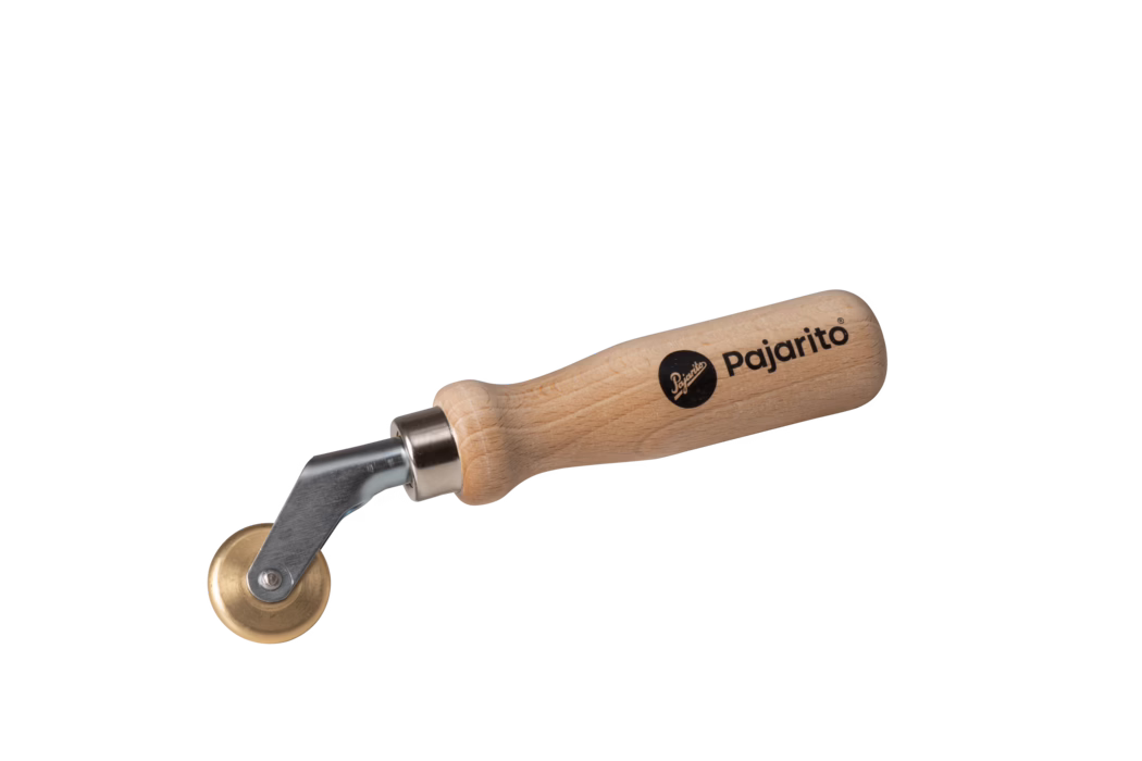 Pajarito_Dummy_Pressure roller PVC-films_034434_2021-02 Une image en gros plan détaillée d'un outil de roulage Pajarito avec une poignée en bois et une roue en métal, conçu pour des tâches spécifiques de bricolage ou de glaçage.